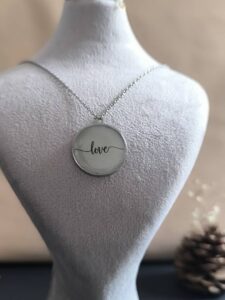 تصویر گردنبند گرد شب‌تاب با نوشته love که در تاریکی با نور سبز می‌درخشد.