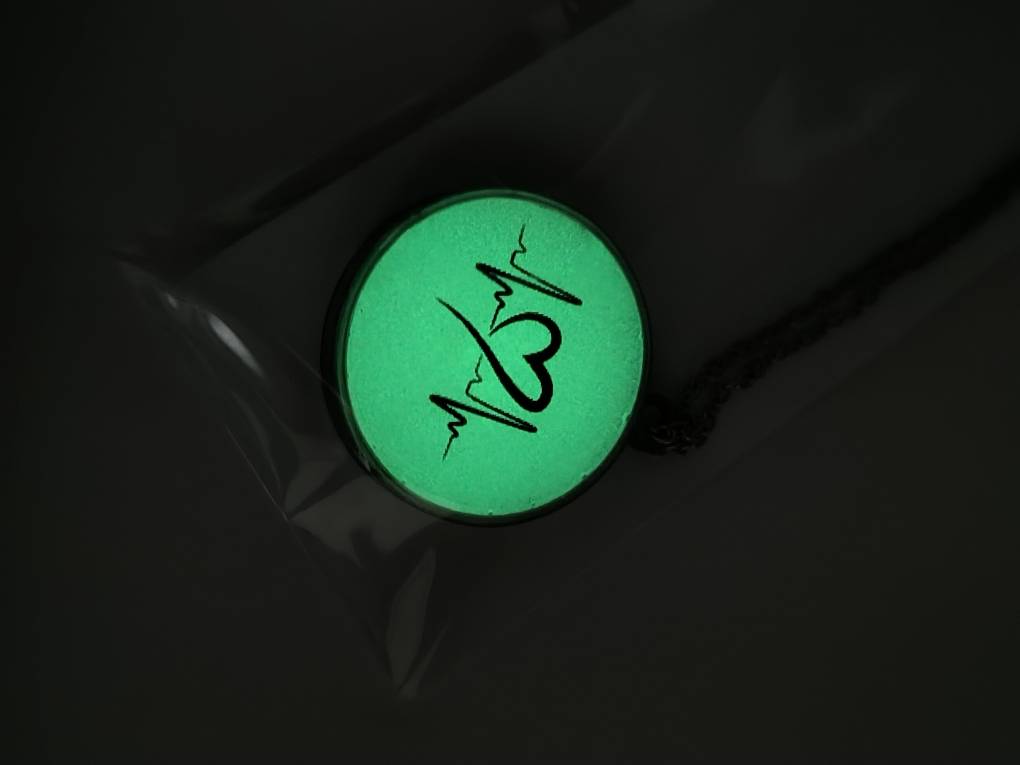 گردنبند شبتاب دایرهای با طرح ضربان قلب و قلب در حال درخشش سبز در تاریکی.