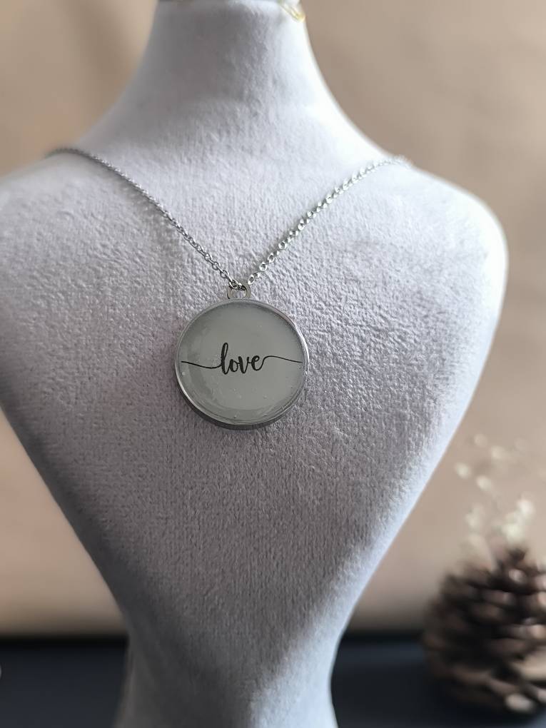 تصویر گردنبند گرد شبتاب با نوشته love که در تاریکی با نور سبز میدرخشد.