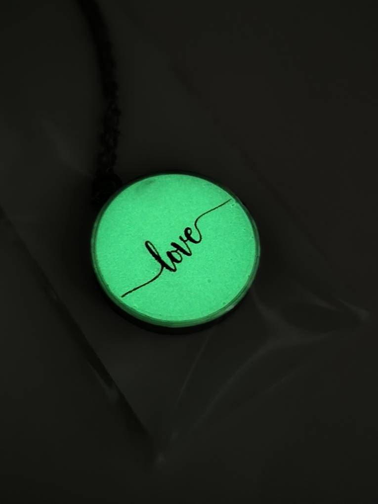 تصویر گردنبند گرد شبتاب با نوشته love که در تاریکی با نور سبز میدرخشد.